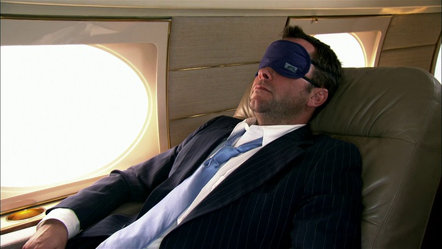 特写商人戴着睡眠面具躺在私人飞机上视频素材