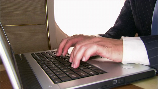 在私人飞机上，商人在笔记本电脑上打字，调整领带视频下载
