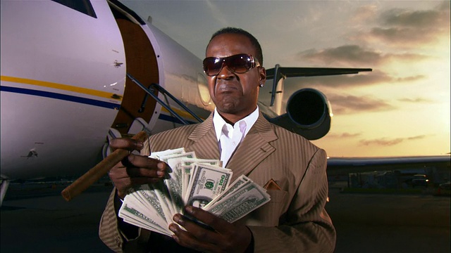 美国加州长滩，私人飞机旁，富商手里拿着雪茄，数着钱视频素材