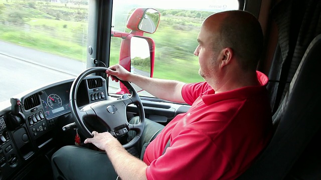 卡车司机坐在驾驶室里，在路上开车视频下载