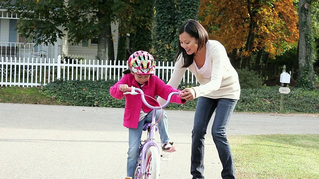 潘佐图女士母亲教小女儿骑自行车/美国弗吉尼亚州里士满视频素材