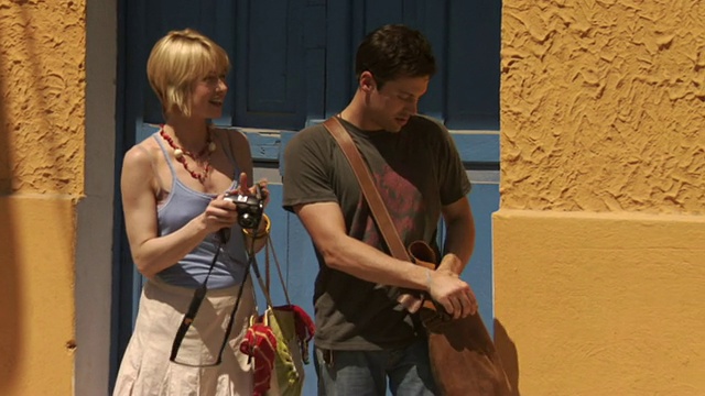 墨西哥梅里达，一名男子在建筑物旁用数码相机给一名女子拍照，然后他们走在街上视频素材