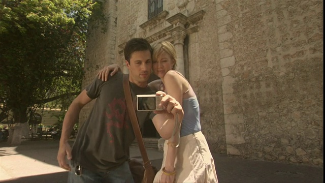 墨西哥梅里达，一对游客夫妇在圣伊尔德丰索大教堂前拍照，然后从拱门进入教堂视频素材