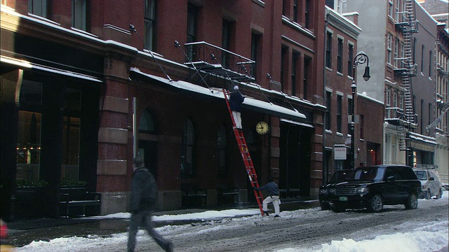 佐曼女士在梯子上打落雨棚上的雪/纽约，纽约，美国视频下载