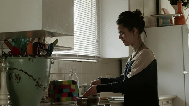 美国犹他州普罗沃的一位年轻女士正在厨房里看邮件和烤面包视频素材