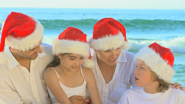 快乐的家庭戴着圣诞帽和唱歌在海滩/开普敦，西开普敦，南非视频素材