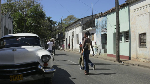 在古巴的圣地亚哥-德-拉斯维加斯，当地人开着旧车在街边购物视频下载