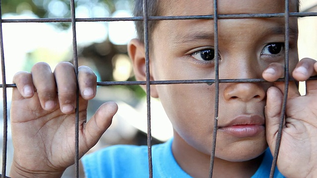 高清贫困-亚洲男孩在围栏后面视频素材