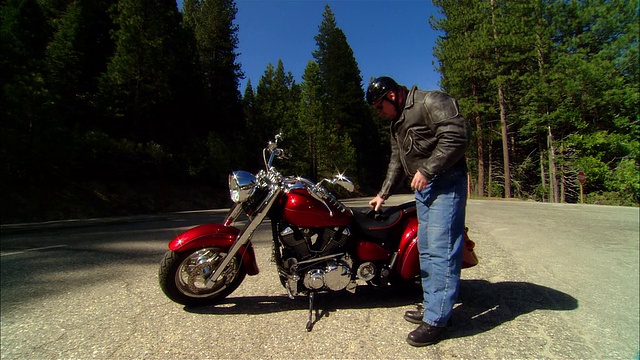 骑摩托车的女士戴上手套，驾驶摩托车在塞拉国家森林/弗雷斯诺县，美国加州视频下载