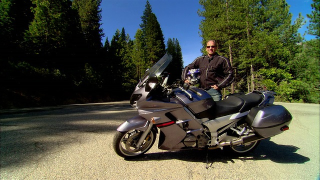 美国加利福尼亚州，塞拉国家森林/弗雷斯诺县，手持摩托车头盔的自行车手站在雅马哈摩托车旁视频素材