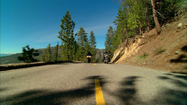 在美国加利福尼亚州的塞拉国家森林/弗雷斯诺县的公路上驾驶摩托车的骑车人视频素材