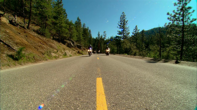 在美国加利福尼亚州的塞拉国家森林/弗雷斯诺县的公路上驾驶摩托车的骑车人视频素材