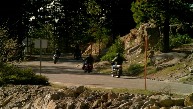 美国加利福尼亚州的塞拉国家森林/弗雷斯诺县，骑摩托车的人在弯弯曲曲的道路上行驶视频素材