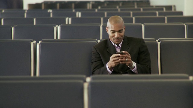 MS Man独自坐在一排椅子上使用手机/美国佛罗里达州杰克逊维尔视频素材