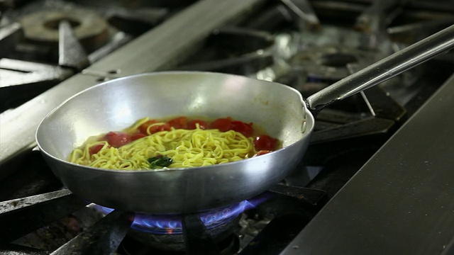 厨师将番茄和罗勒意大利面放入平底锅的特写镜头视频素材