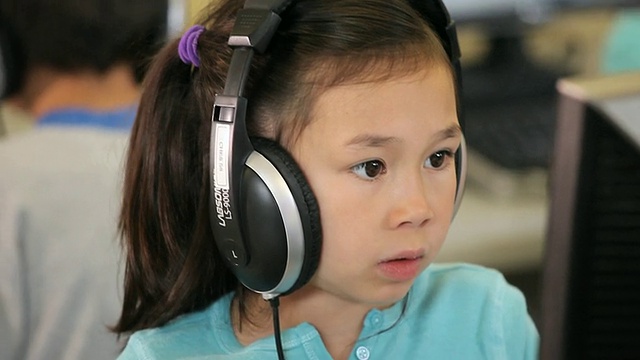 美国弗吉尼亚州里士满的学生戴着耳机坐在计算机实验室里视频素材