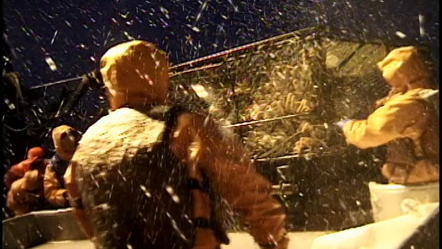 雪夜，美国阿拉斯加州白令海，渔民们在甲板上打开蟹笼，把它们扔到桌子上分拣视频素材