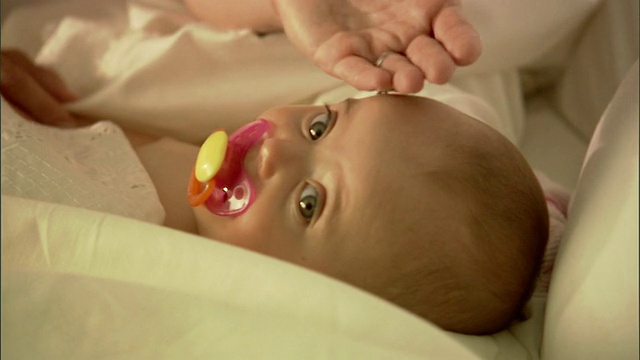 CU，女婴(6-9个月)含奶嘴躺在床上视频素材
