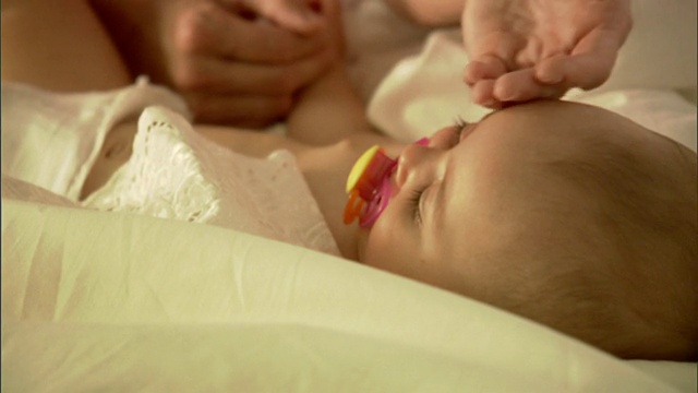 CU，女婴(6-9个月)含奶嘴躺在床上视频素材