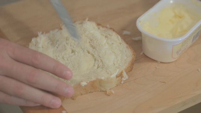 把黄油从容器里抹出来，然后抹在面包上。视频下载