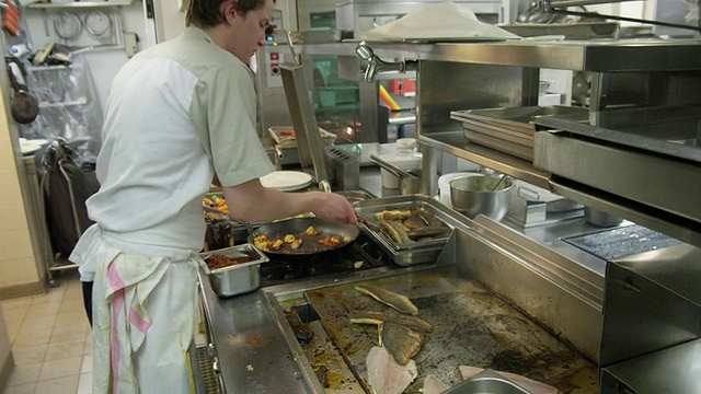 POV厨师工作在一个餐馆厨房的热板烹饪鱼视频下载