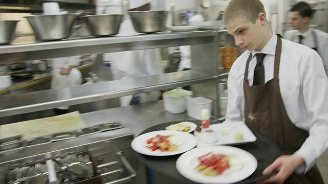 POV侍者端着糖果托盘从餐厅厨房到餐厅;相机是服务员视频下载