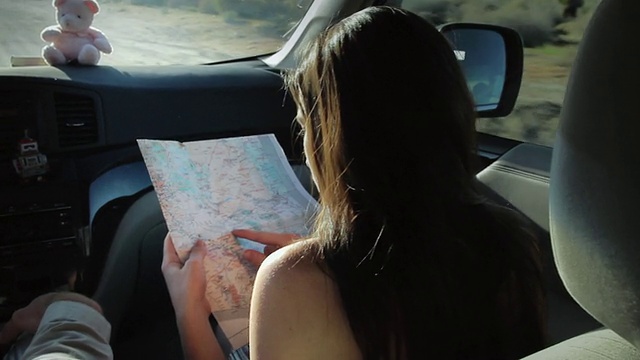 一对夫妇开车，女人看地图，向男人寻求建议。/美国加利福尼亚州，帕姆代尔视频素材