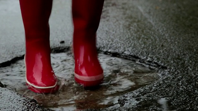 红色橡胶靴在路边的水坑里跳舞/丹麦哥本哈根，Sjaelland视频下载