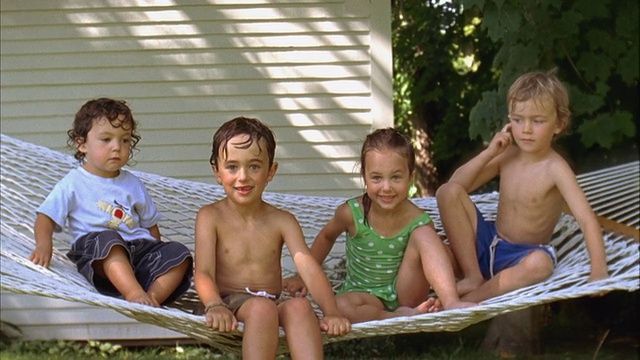 MS，美国，缅因州，雅茅斯，四个微笑的孩子(2- 3,4 - 5,6 -7)湿头发坐在吊床上视频下载
