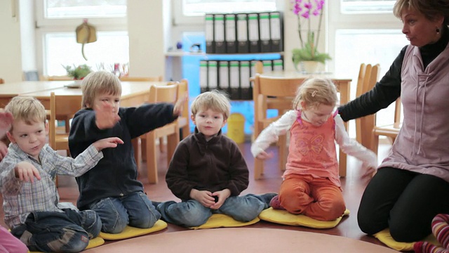 德国勃兰登堡波茨坦，教育家和孩子们围坐在地板上用手指玩耍视频下载