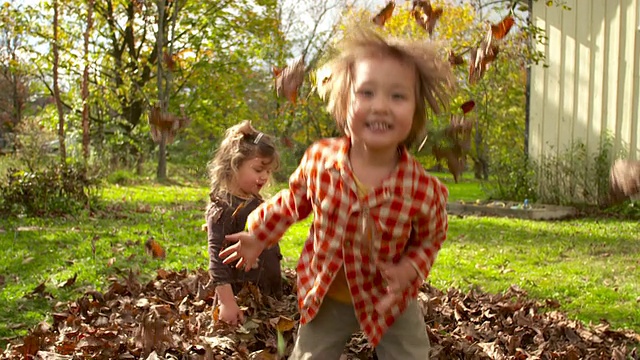 WS SLO MO DS拍摄的两个孩子在树叶/蒂沃利，纽约，美国视频素材