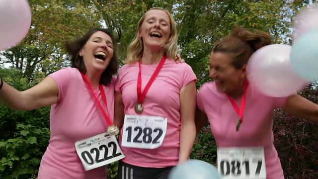 三个40多岁的女人参加过慈善长跑。粉红色的衬衫和蓝色和粉色的气球视频下载