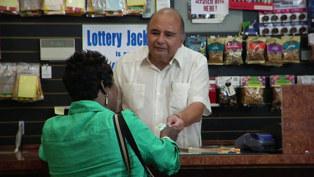 女士在便利店买刮花票/女士在柜台刮花票/女士获胜后举起手臂/布鲁克林，纽约视频下载