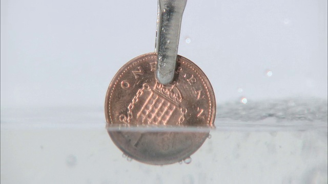 将2便士硬币放入溶液中除去铜，使其变成银视频素材