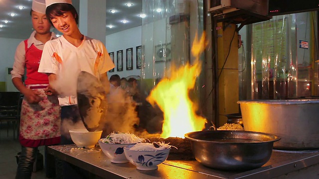 中国陕西西安夜市，厨师在明火上烹饪视频下载