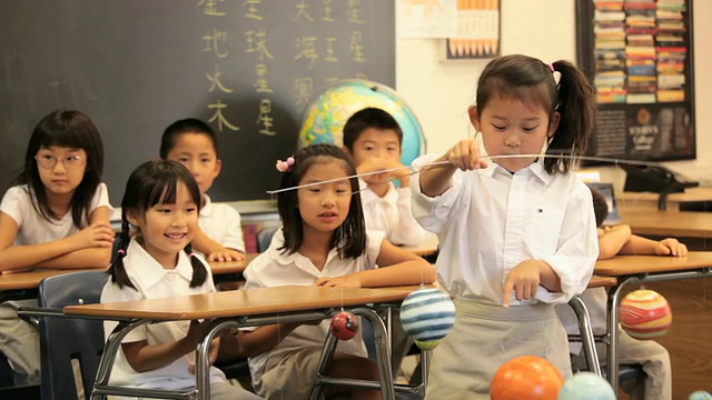 亚洲儿童在教室向相机展示模型太阳系/里士满，弗吉尼亚州，美国视频下载
