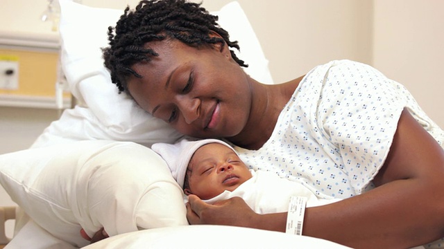 美国弗吉尼亚州里士满，新妈妈抱着新生儿躺在病床上视频下载