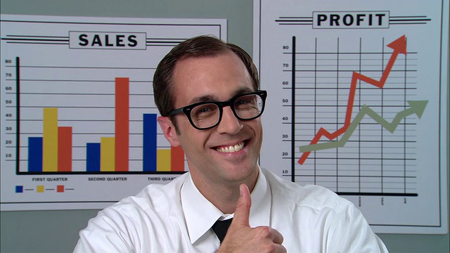 CU肖像商人戴着眼镜微笑，竖起大拇指，在图表前做OK手势/纽约市视频素材