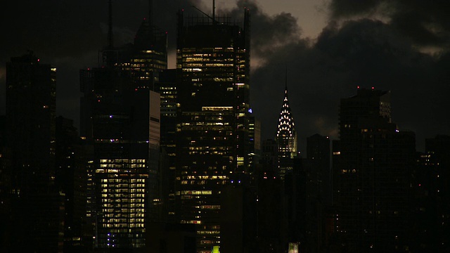 静态镜头的克莱斯勒大楼和邻近的天空照亮摩天楼，太阳升起在阴云密布的曼哈顿天空视频素材