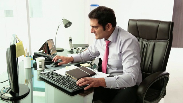 一个商人在办公室里用台式电脑工作视频素材