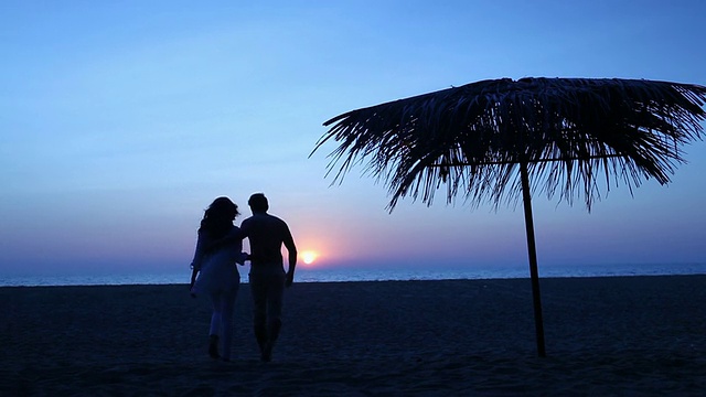 后视图的一个年轻夫妇浪漫的海滩上日落视频素材