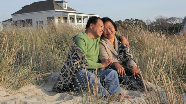 美国弗吉尼亚州伊斯特维尔海滩沙丘上，老夫老妻坐在毯子下视频下载
