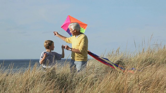 MS TS小男孩放风筝，与祖父在海滩沙丘上散步/伊斯特维尔，美国弗吉尼亚州视频素材