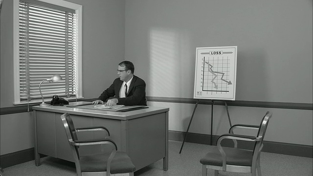 B/W MS沮丧的商人坐在桌子旁边的图表显示损失/男人断了铅笔/纽约市视频素材