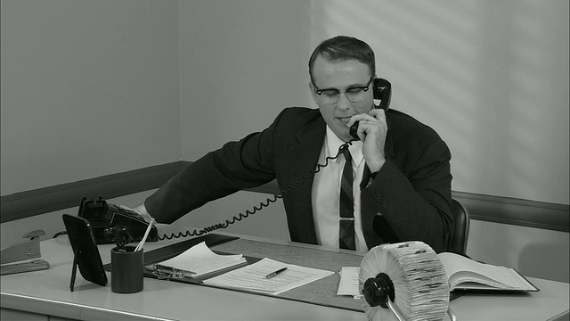 B/W MS快乐的商人在办公室打电话/男人挂电话后靠在椅子上，看起来很高兴/纽约视频素材