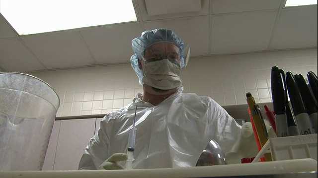 低角度手持-验尸官在验尸过程中将液体注入小瓶中。/美国视频素材