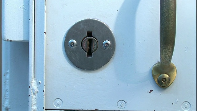 中泛左放大-双手关闭拘留室的门，用钥匙转动锁。/美国视频下载