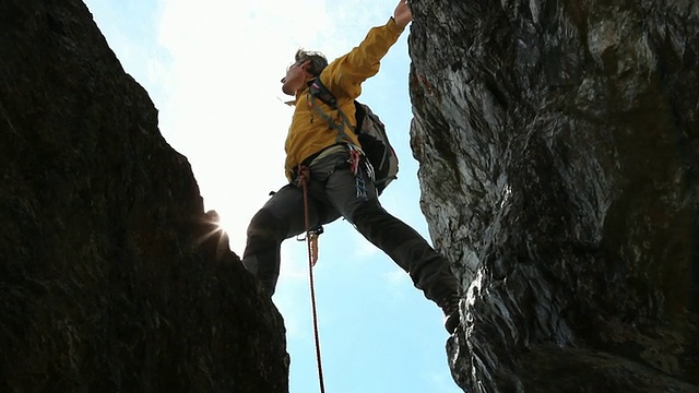 登山者攀登陡峭的岩石裂缝到顶部，伸开双臂视频素材