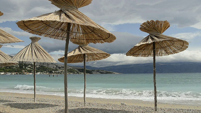 克罗地亚克拉克岛巴斯卡湾海滩上的芦苇伞视频素材