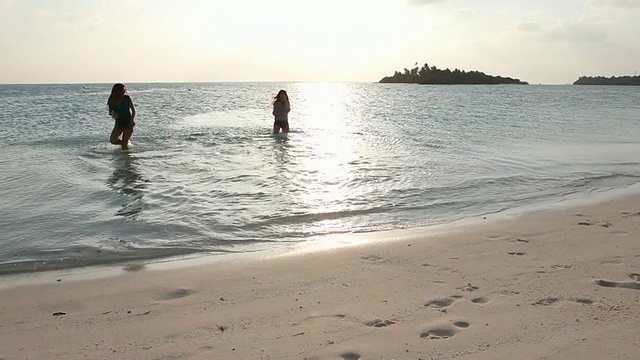 一群十几岁的女孩在白色沙滩上奔跑，溅起水花视频下载